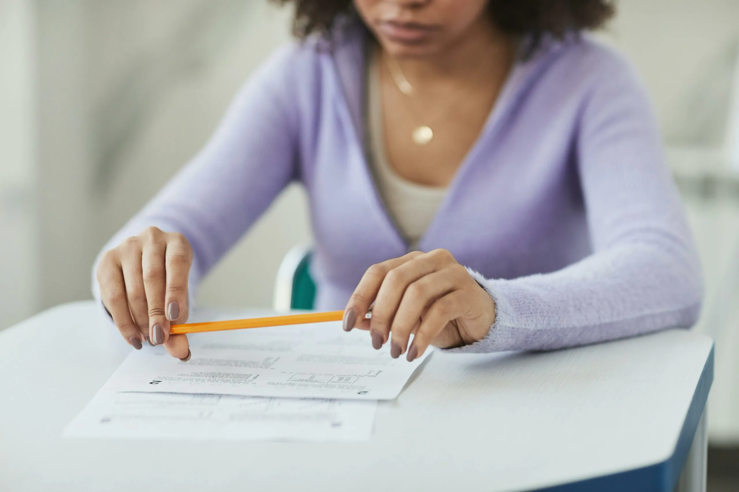 A person twirling a pencil while staring at a nursing exam thinking through their NCLEX test taking strategies
