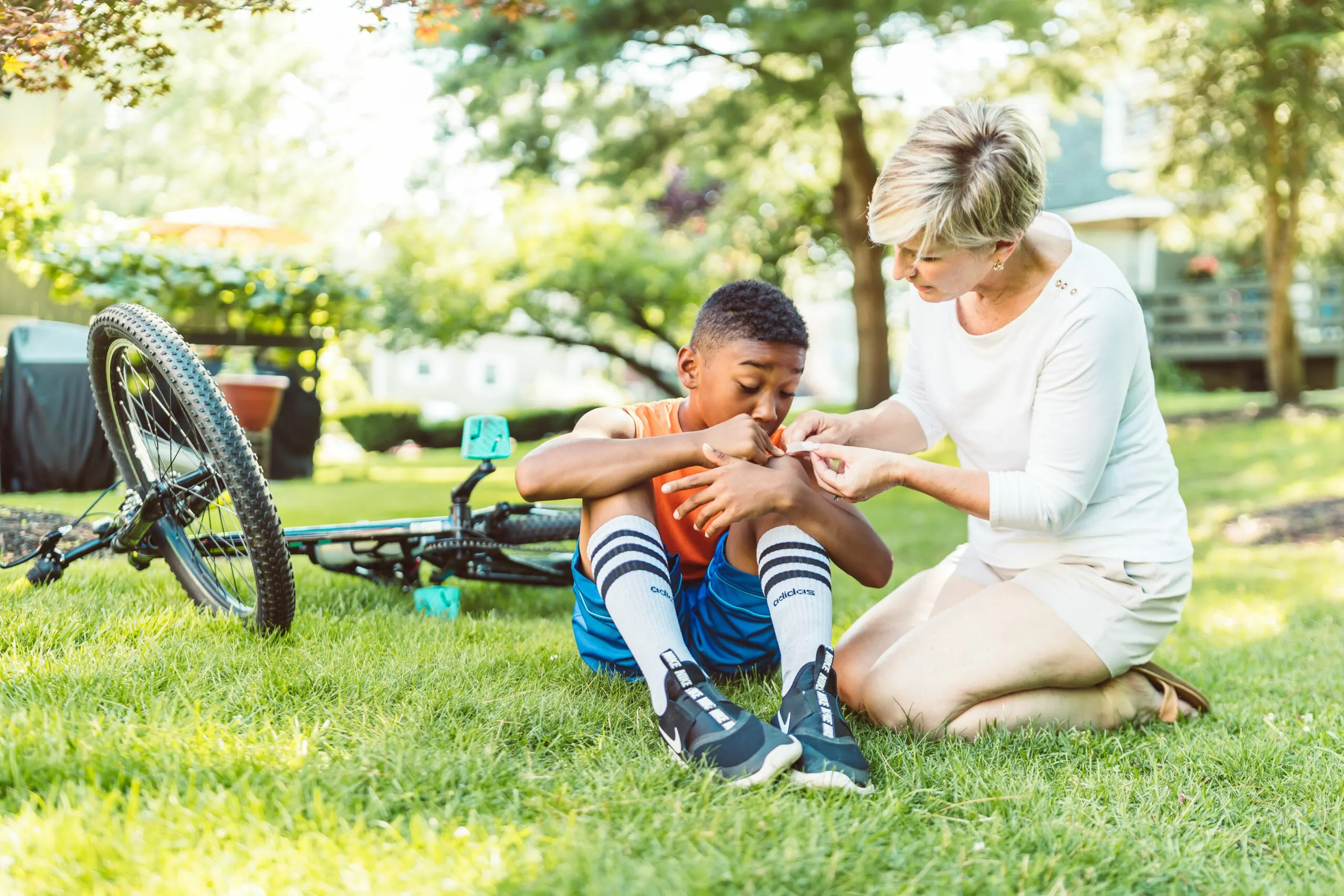 Camp nurse assistant applying a bandage to a child's arm outdoors