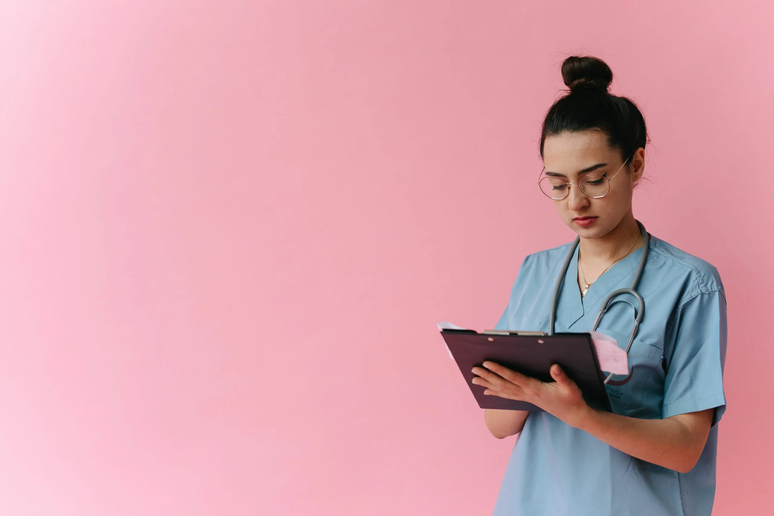Registered nurse in scrubs reviewing patient notes on a clipboard