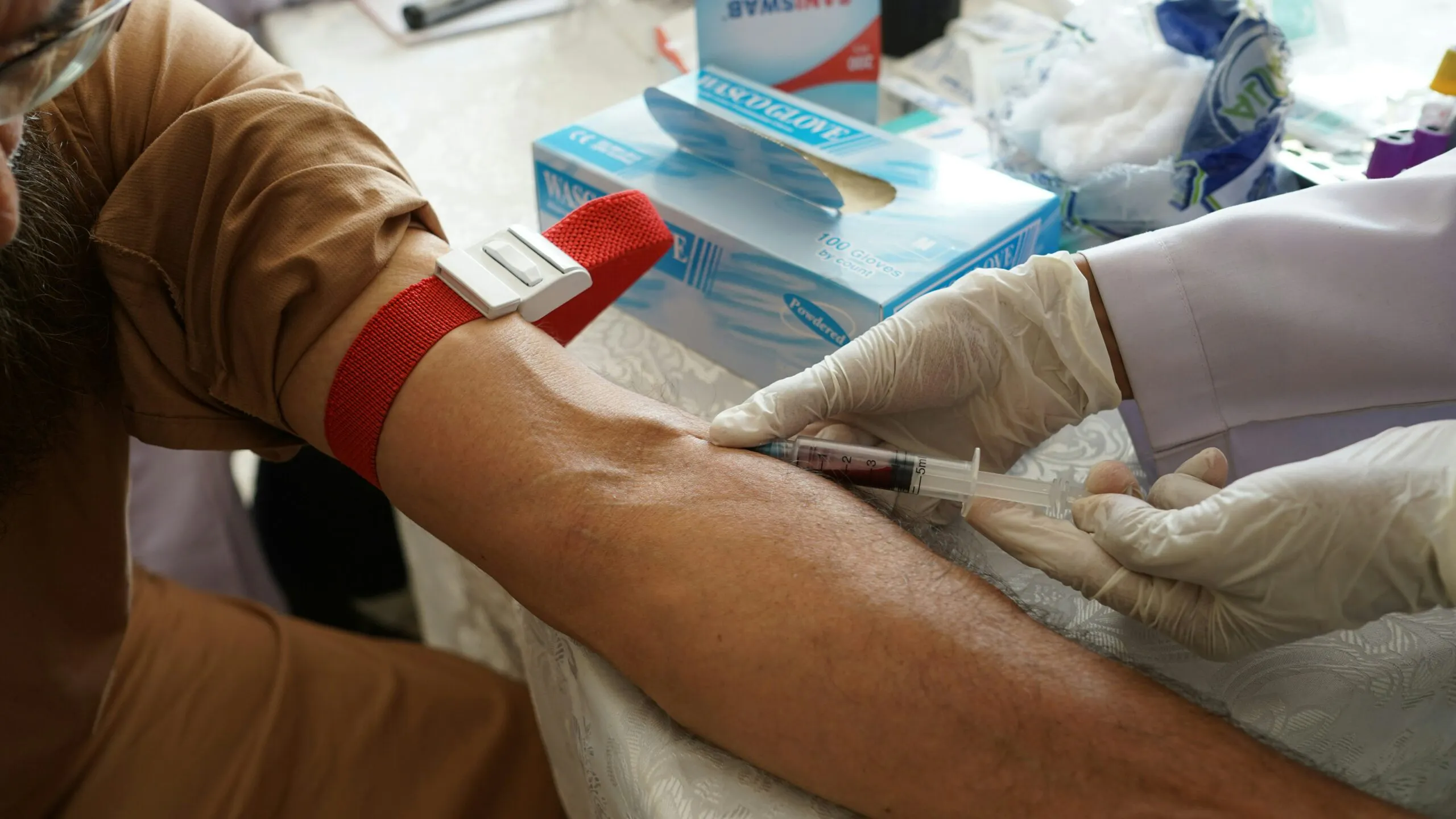 Phlebotomist drawing blood from a patient's arm during a clinical procedure