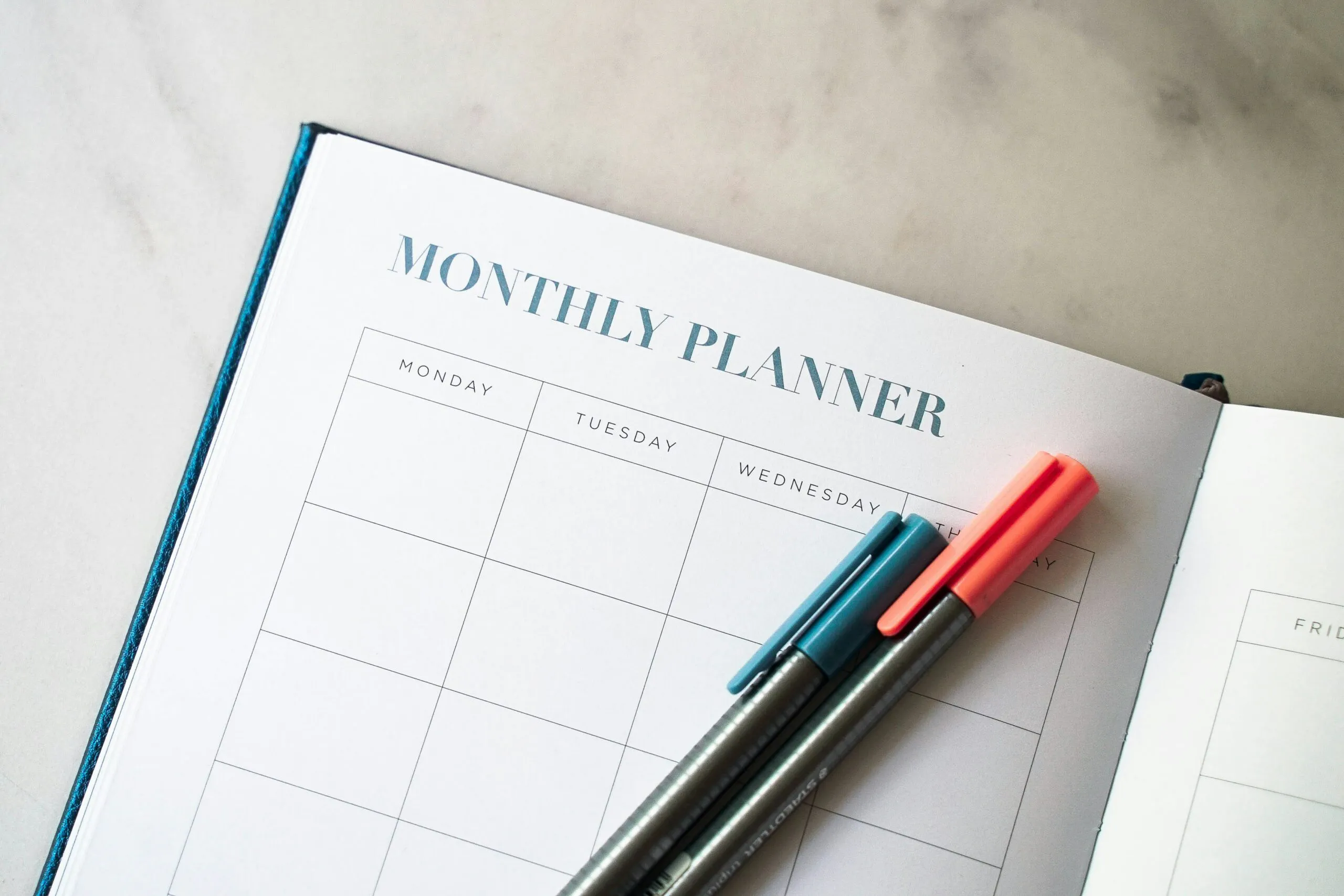 Open monthly planner with colored pens used to track nursing school deadlines