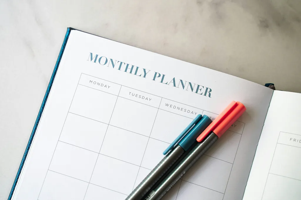 Open monthly planner with colored pens used to track nursing school deadlines