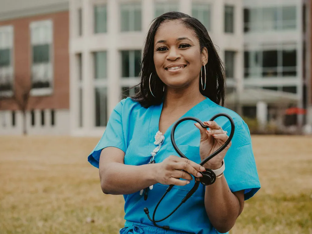 Nurse in scrubs outside a hospital holding a stethoscope, reflecting on whether CCRN certification is worth the cost and study time