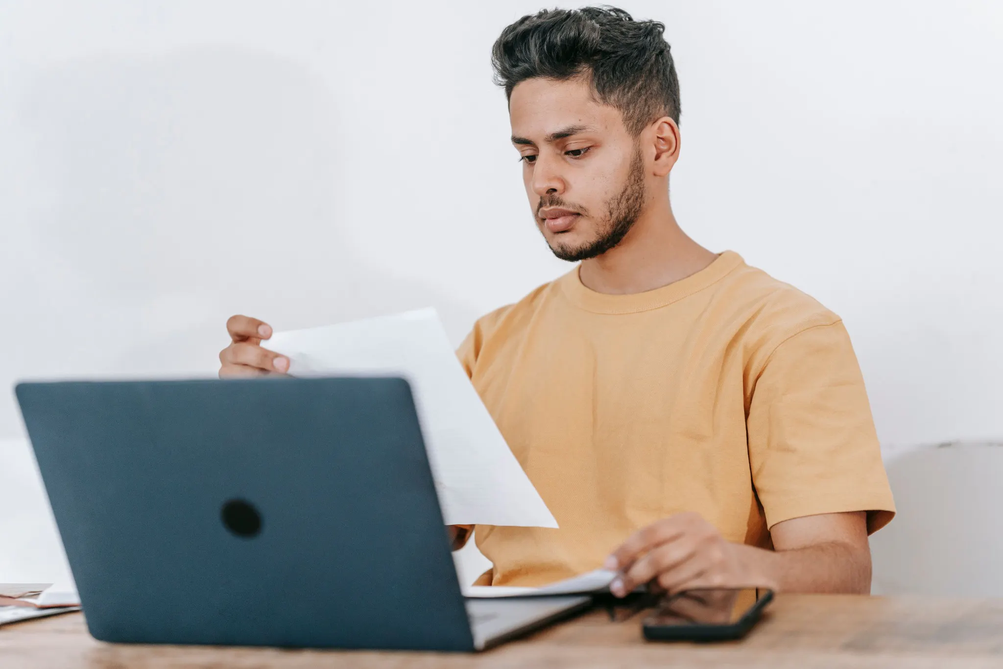 Student reviewing a paper beside a laptop while checking exam results