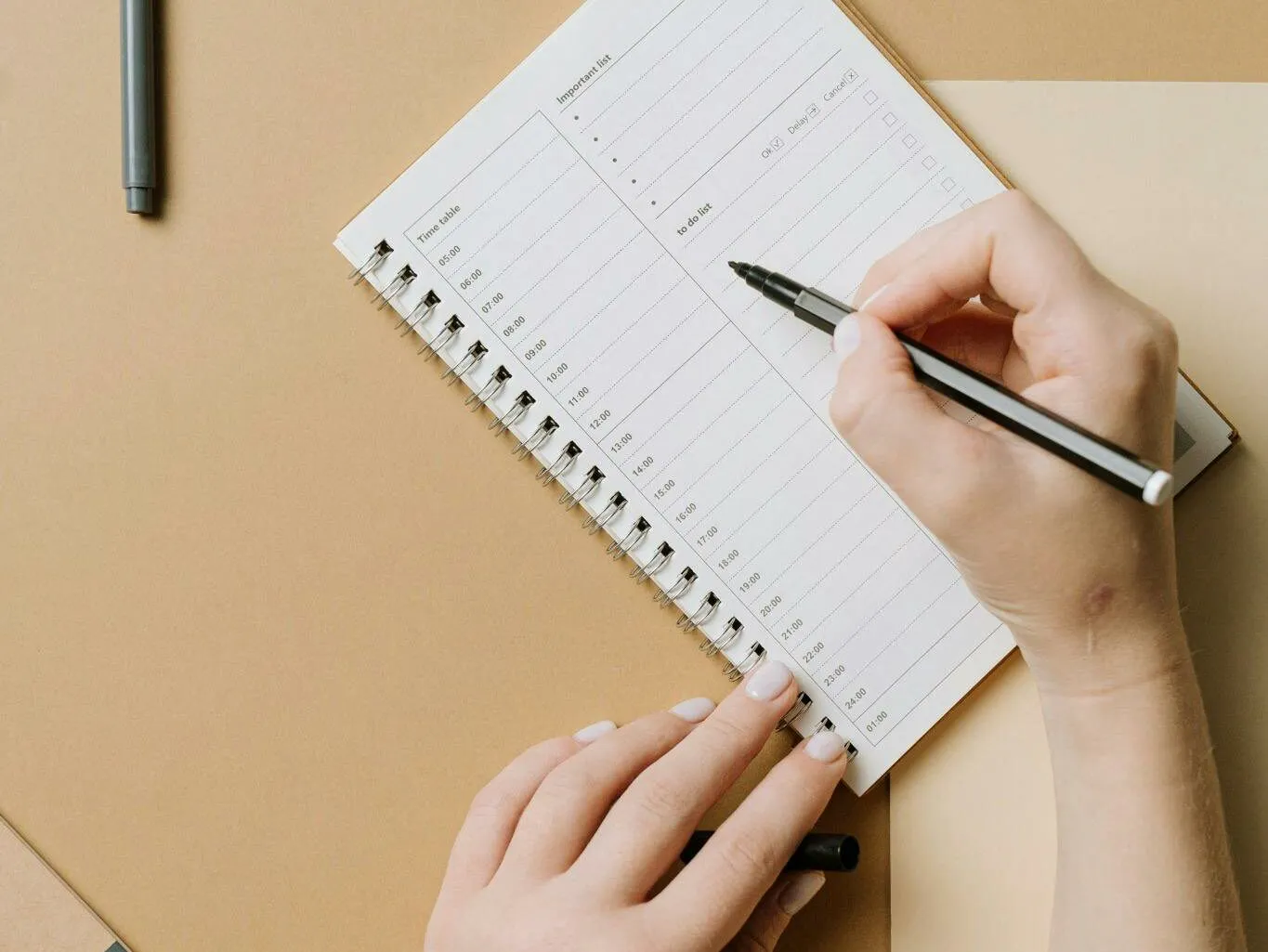 Hands writing in a daily planner with a timetable and checklist
