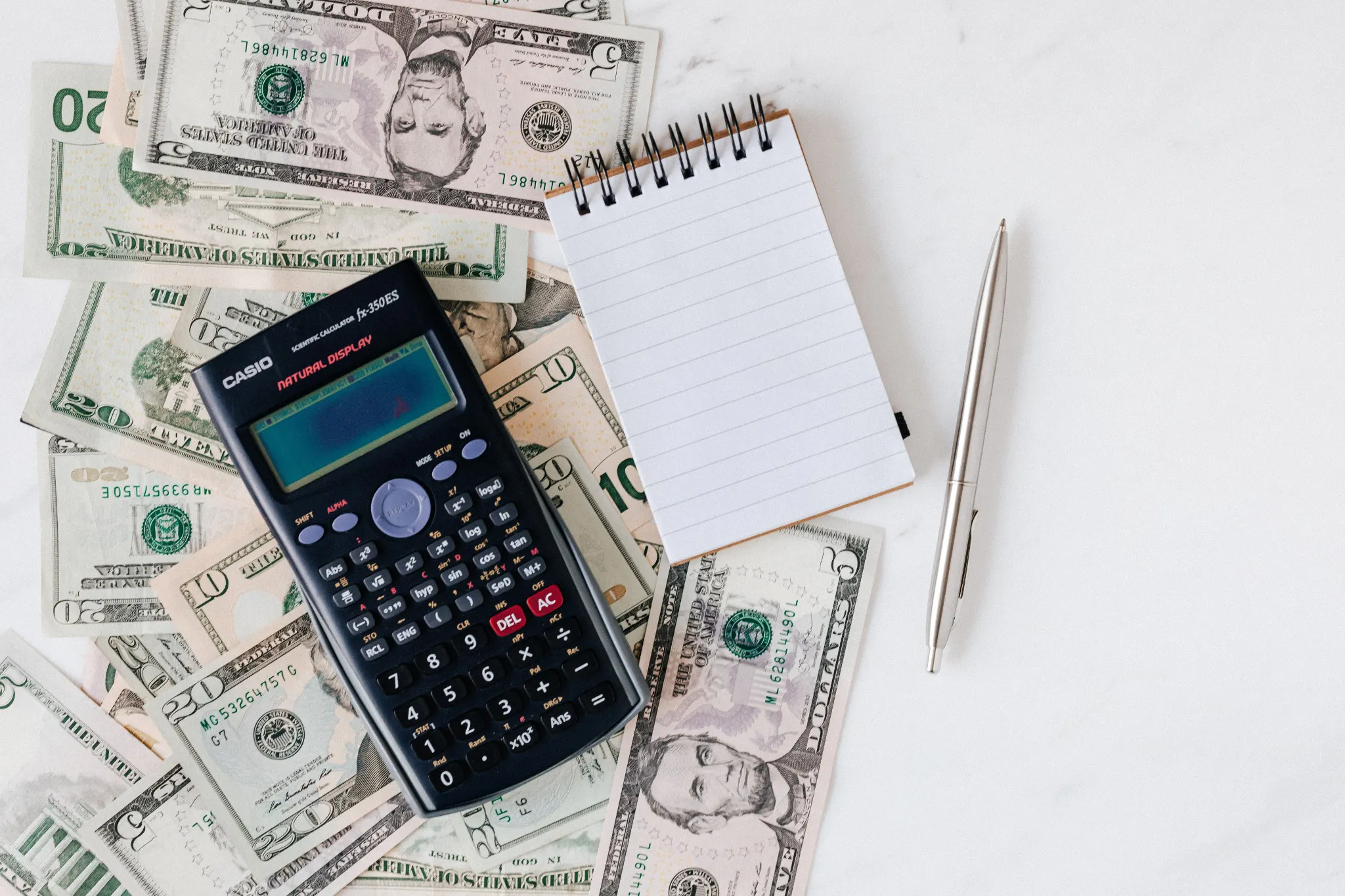 US dollars, calculator and notepad illustrating a budget for the cost of NCLEX licensure
