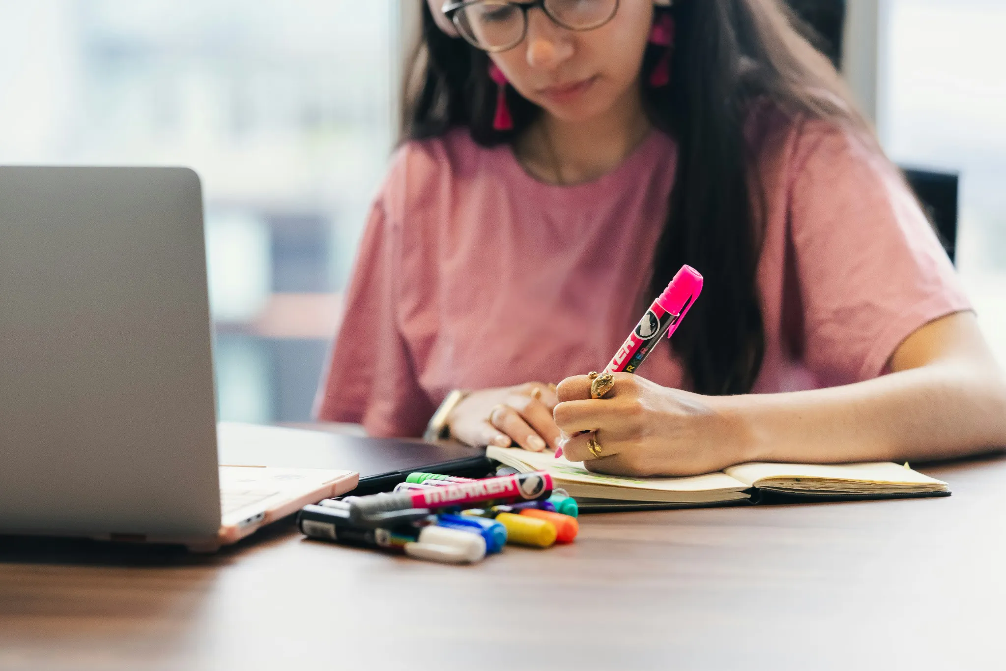 Woman writing notes beside a laptop, illustrating preparation and NCLEX test taking strategies